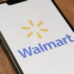 A smartphone displays the Walmart logo on its screen while resting on a wooden surface.