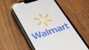 A smartphone displays the Walmart logo on its screen while resting on a wooden surface.
