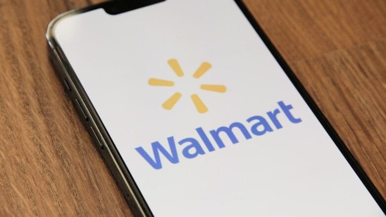 A smartphone displays the Walmart logo on its screen while resting on a wooden surface.