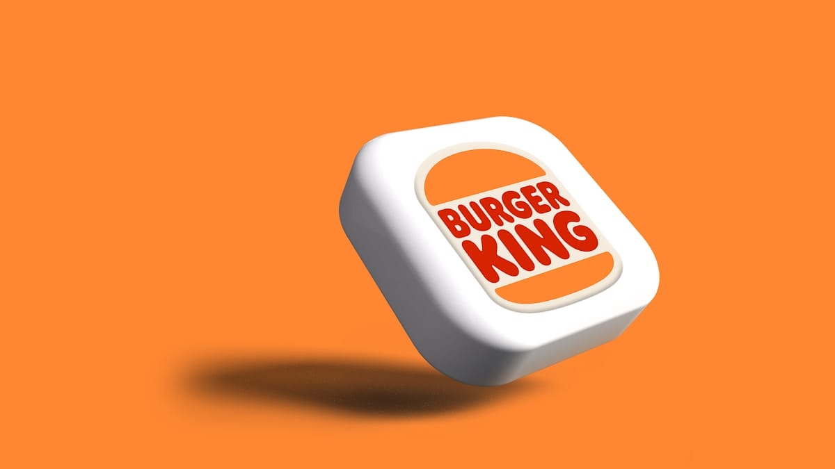 A white 3D square with the Burger King logo floats against an orange background, casting a shadow below.