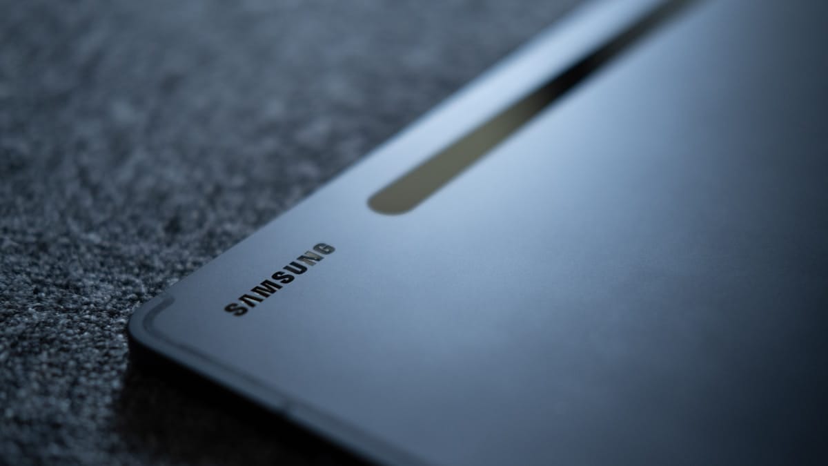 Close-up of a Samsung tablet placed on a textured dark surface, showing the brand logo and part of the device’s back.
