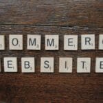 Scrabble tiles spelling out Ecommerce Website are arranged on a wooden surface.