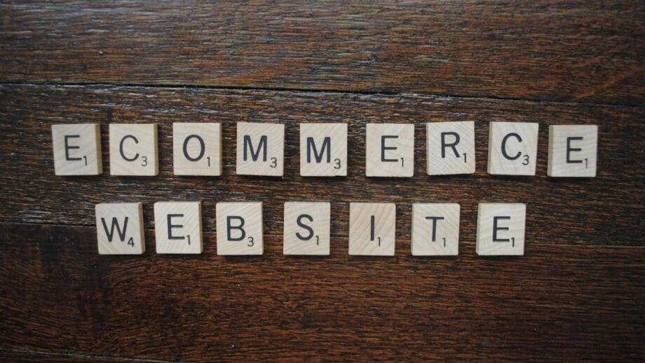 Scrabble tiles spelling out Ecommerce Website are arranged on a wooden surface.