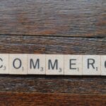 Wooden Scrabble tiles spell out Ecommerce on a dark wooden surface.