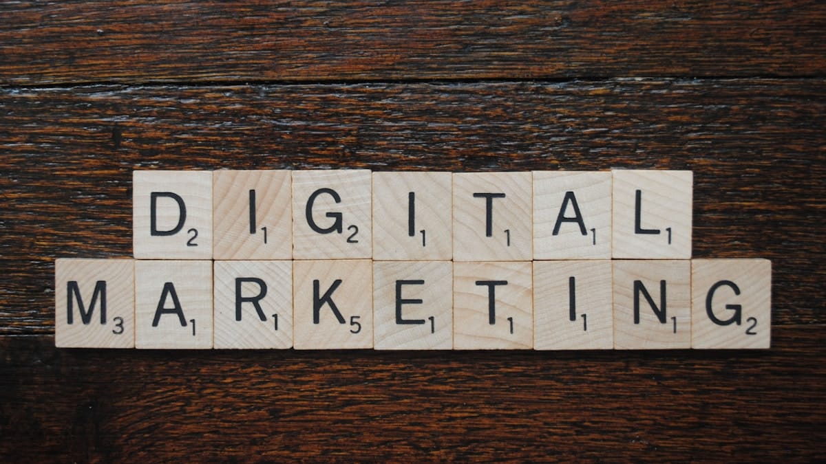 Scrabble tiles spell out DIGITAL MARKETING on a dark wooden surface.