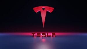 Red Tesla logo above the word TESLA in bold 3D letters, set against a dark background with pink and blue lighting effects.