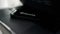 A smartphone displaying the OpenAI logo rests on a laptop keyboard.
