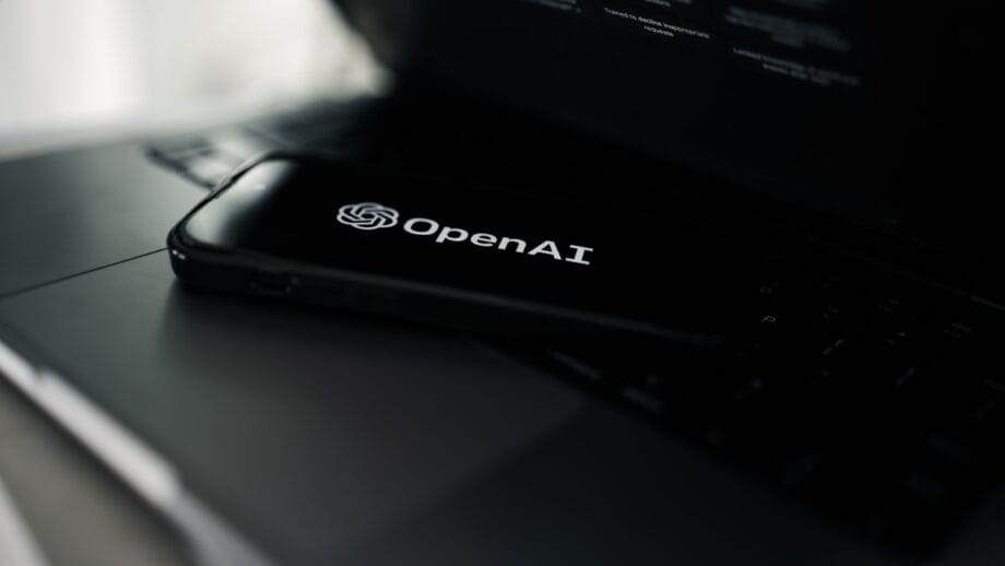 A smartphone displaying the OpenAI logo rests on a laptop keyboard.
