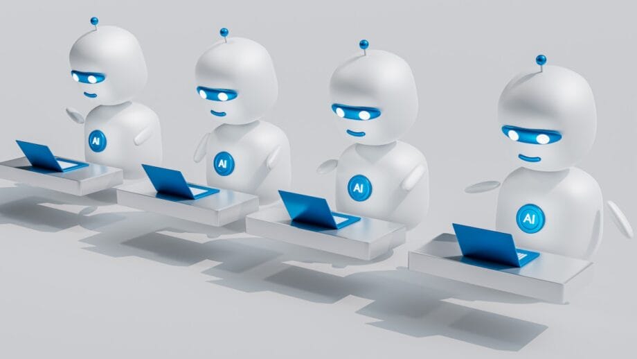 Four white AI robots with blue accents sit at desks, using laptops in a row, against a plain light background.