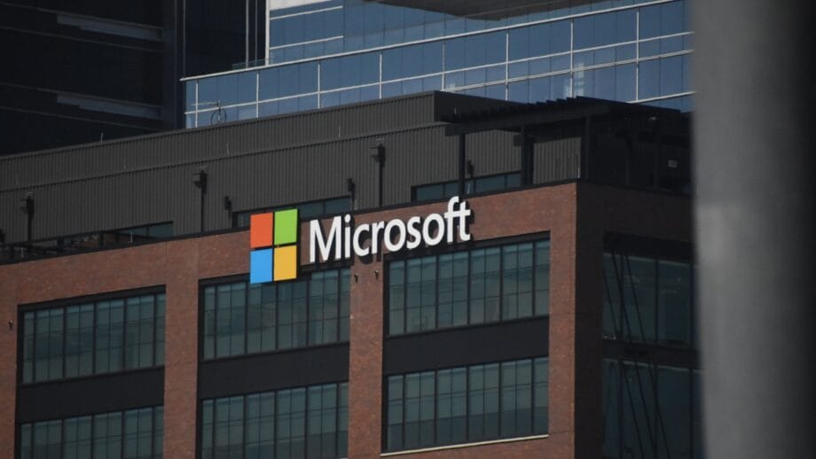 The Microsoft logo is displayed on the exterior of a modern, multi-story office building.