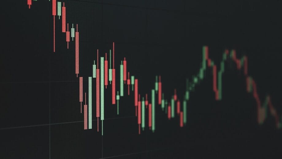 A digital candlestick chart displays fluctuating prices, with red and green bars indicating market movement over time.