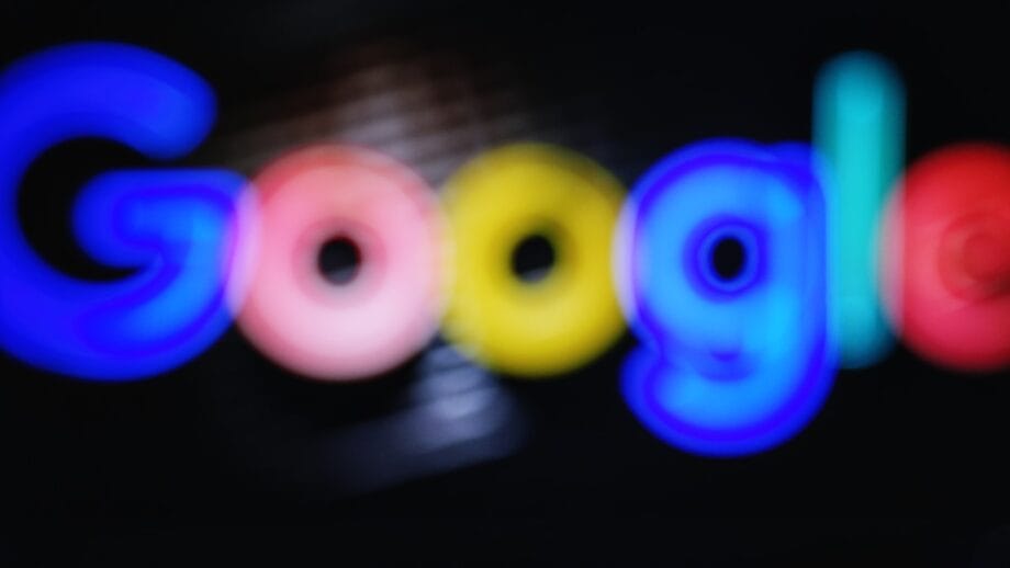 The word Google in colorful, blurred neon-style letters against a dark background.