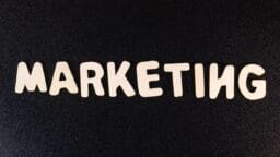 The word MARKETING spelled out in large, light-colored letters on a textured black background.