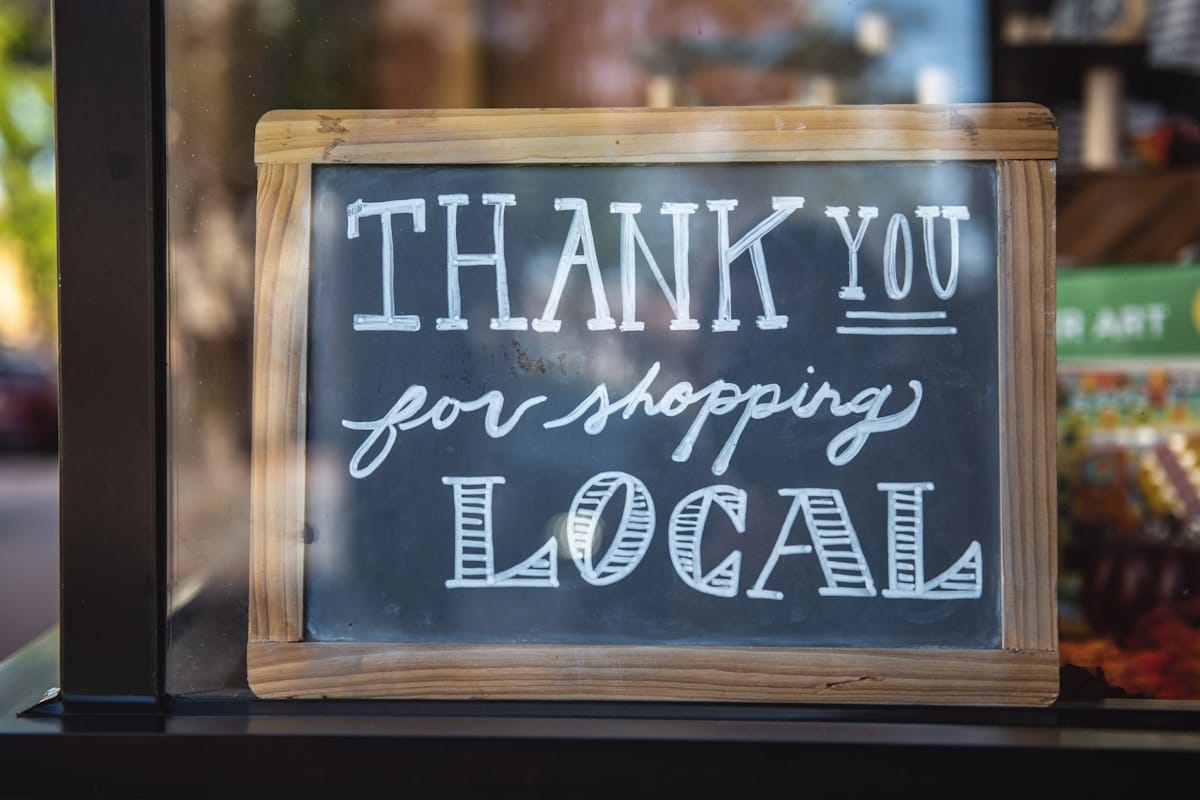 A chalkboard sign with the words Thank you for shopping local written in white letters.