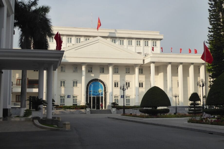 A grand white building with flags is shown.
