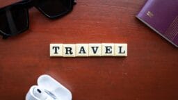 the word travel spelled with scrabbles on a wooden table