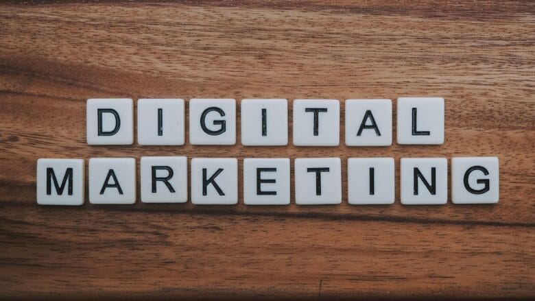 White letter tiles spell out DIGITAL MARKETING on a wooden surface.