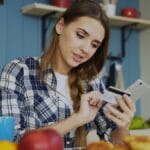 Woman using credit card with smartphone at table