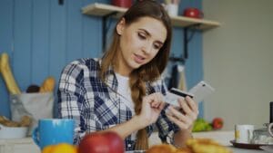 Woman using credit card with smartphone at table