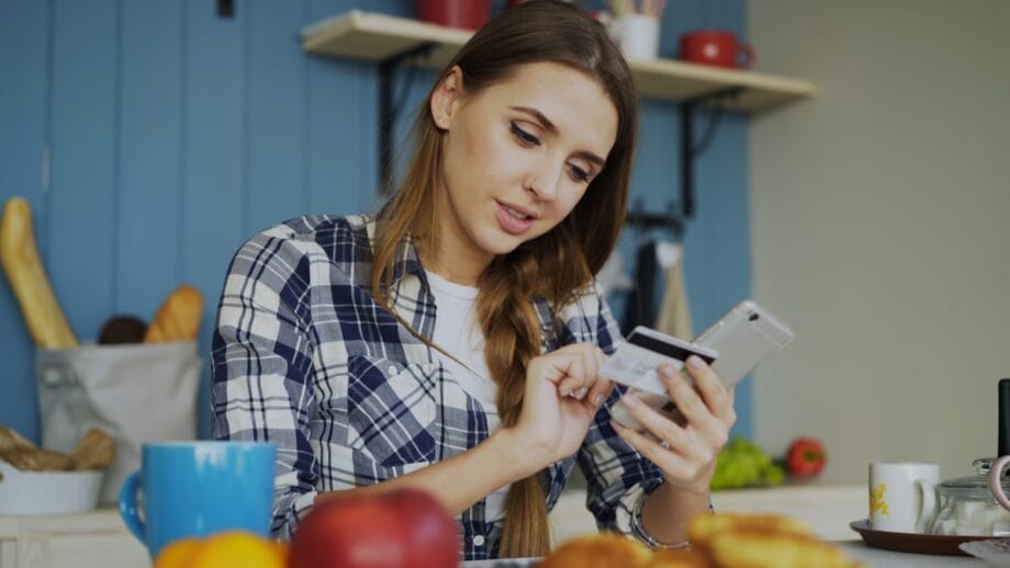 Woman using credit card with smartphone at table