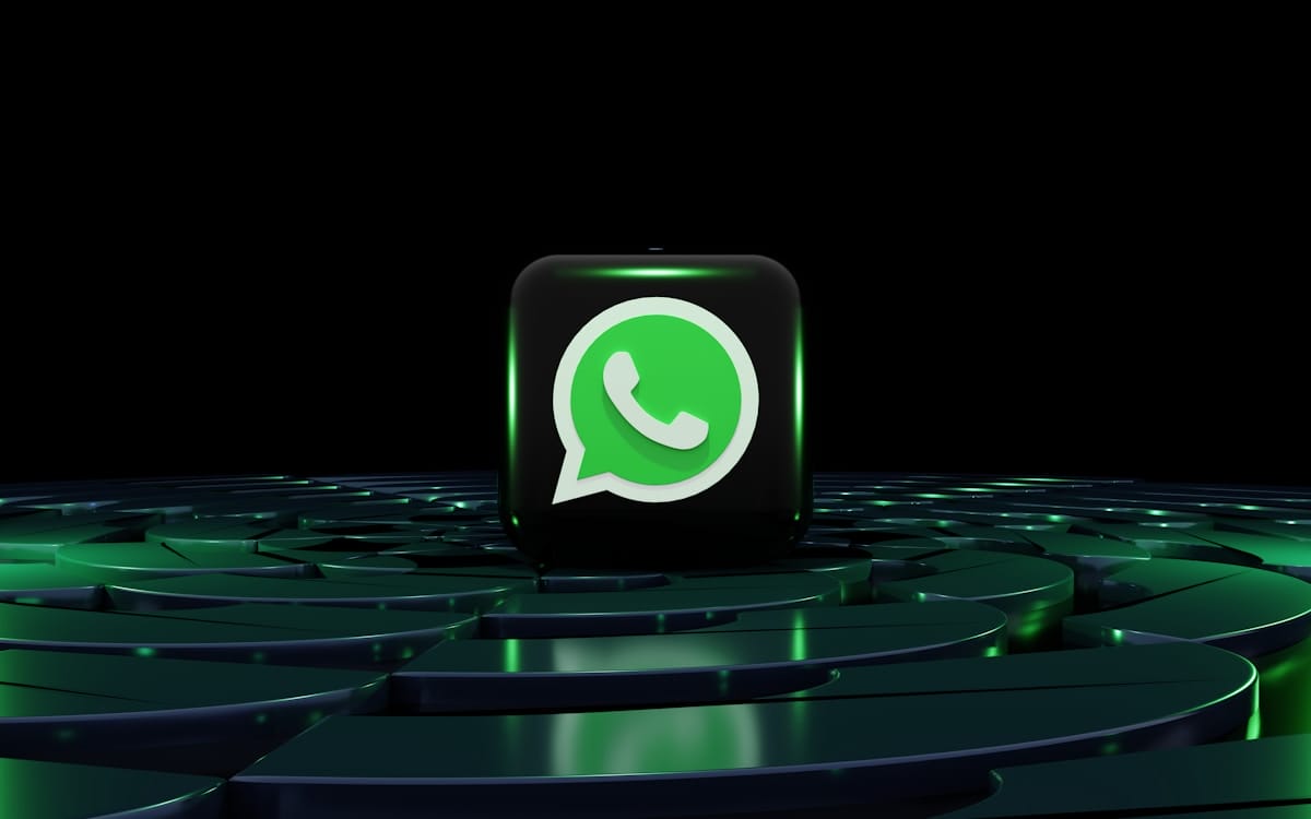 A 3D WhatsApp logo cube sits on a dark, glowing, circular platform with green highlights against a black background.