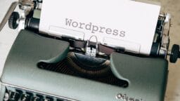 A typewriter with a sheet of paper displaying the word Wordpress typed in large, clear letters.