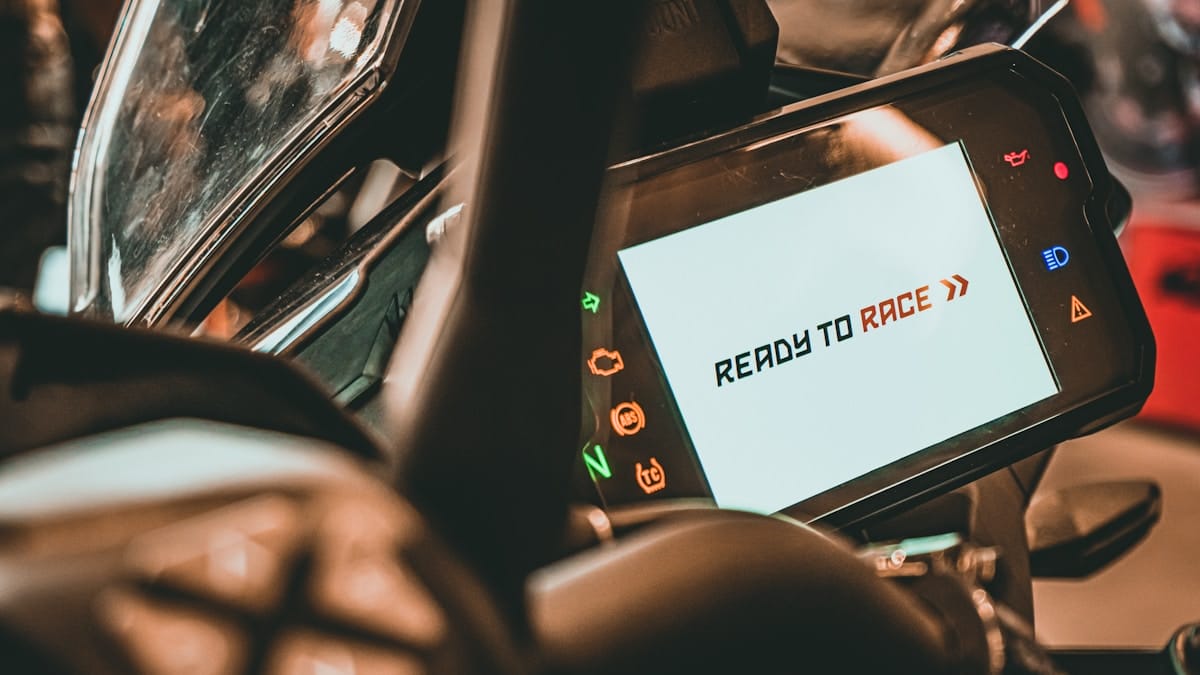 Close-up of a motorcycle digital dashboard displaying the message READY TO RACE in black and orange text.