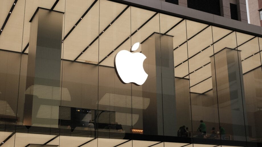 An apple logo is reflected in the glass of a building