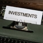 a close up of a typewriter with a paper that reads investments