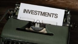 a close up of a typewriter with a paper that reads investments