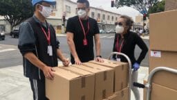 3 men in black polo shirt standing beside brown cardboard boxes