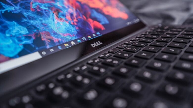 A close-up of a Dell laptop keyboard with a colorful abstract wallpaper displayed on the screen.