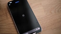 A smartphone displaying the ChatGPT loading screen rests on a wooden surface.