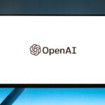 A computer monitor displays the OpenAI logo and name on a plain white background.