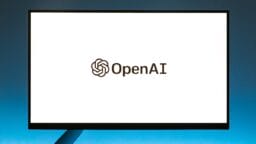 A computer monitor displays the OpenAI logo and name on a plain white background.