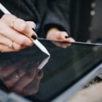 A person uses a stylus to highlight text on a tablet screen.