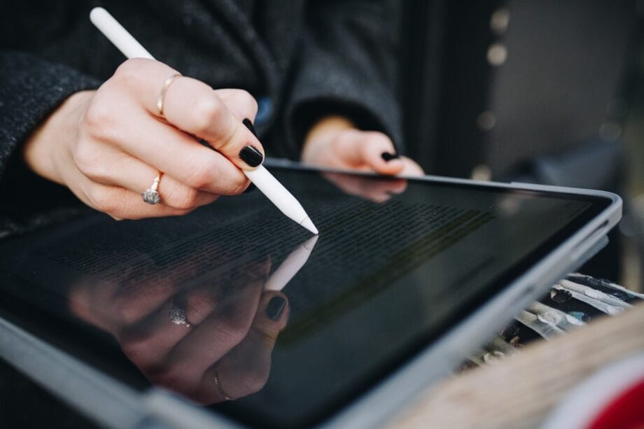 A person uses a stylus to highlight text on a tablet screen.