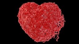 A red heart shaped object with a black background