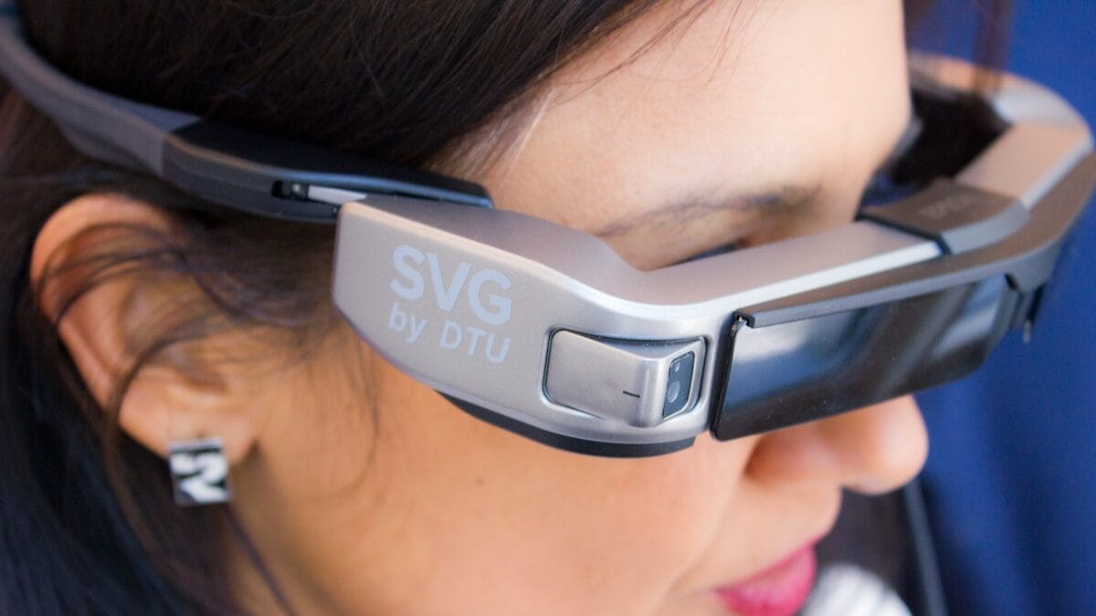 Close-up of a woman wearing augmented reality smart glasses labeled SVG by DTU.