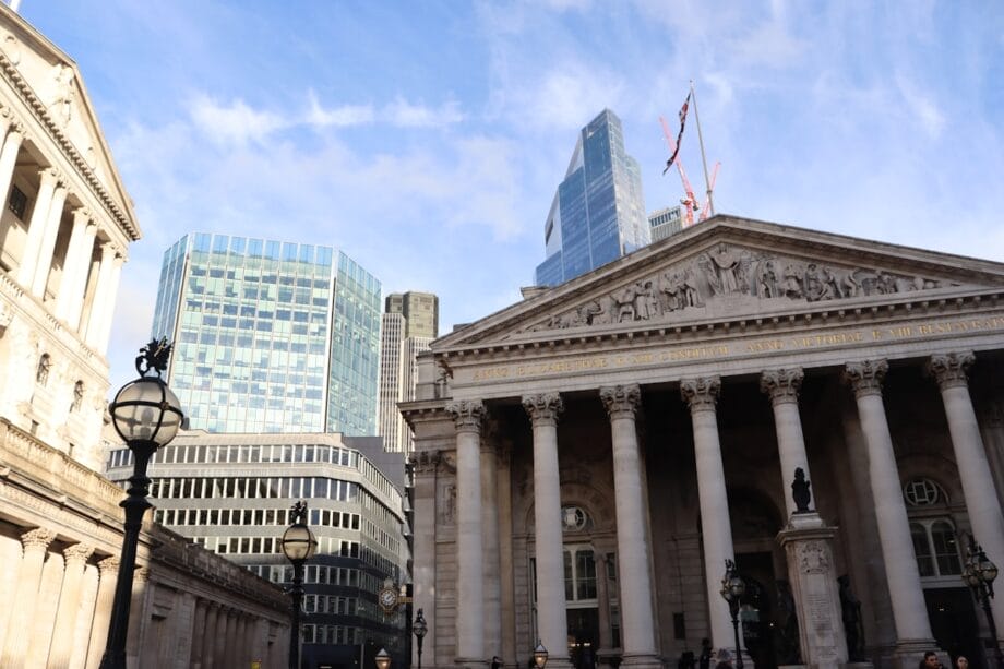 A neoclassical building with columns in front of modern glass skyscrapers under a blue sky with some clouds.