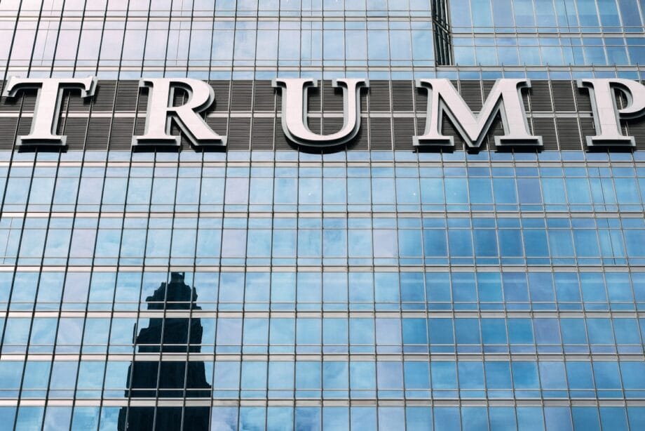 man in black jacket standing in front of glass building