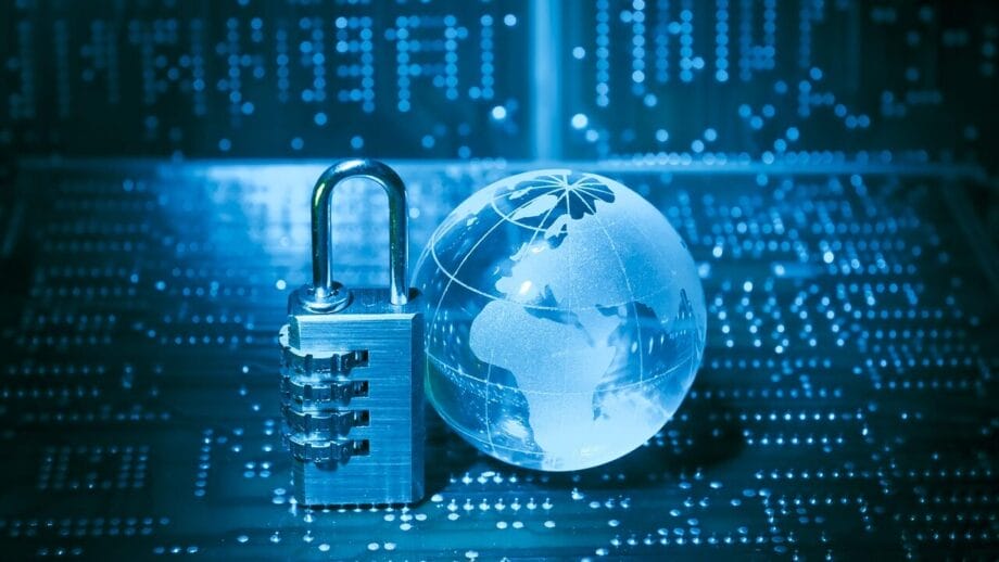 A combination padlock and a glass globe sit on a circuit board, symbolizing cybersecurity and data protection.