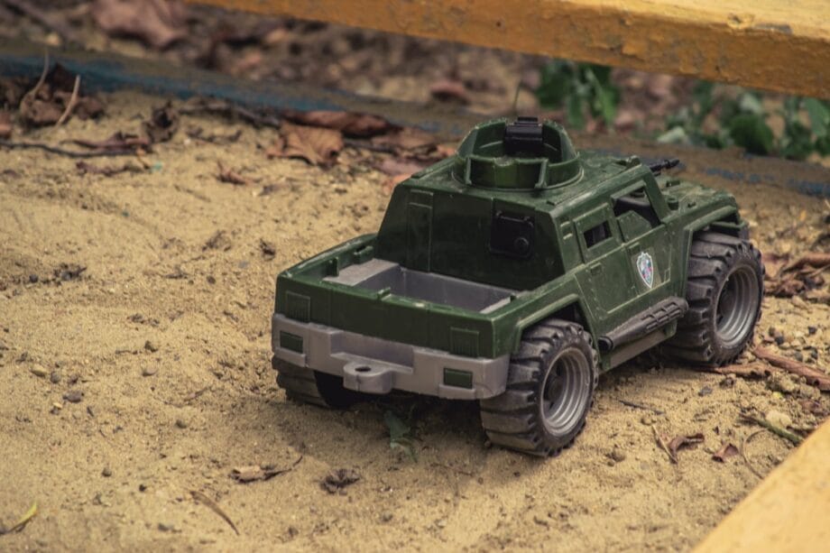 A green toy military vehicle on sand