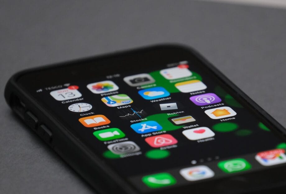 A close-up of a smartphone displaying various app icons on its home screen, including Maps, Photos, and Weather.