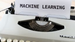 A typewriter with a sheet of paper displaying the words MACHINE LEARNING typed in uppercase letters.