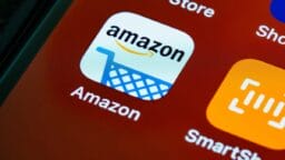 Close-up of a smartphone screen showing the Amazon app icon, featuring a shopping cart and the Amazon logo.