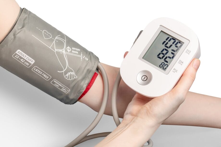 A digital blood pressure monitor displays a reading of 109/82 on a persons arm.