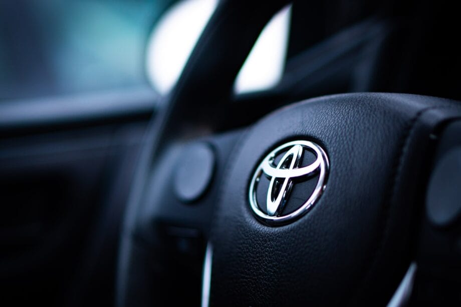 Close-up of a Toyota car steering wheel with the Toyota logo prominently displayed in the center.