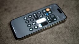 A smartphone displaying the control center screen rests on a gray textured surface.