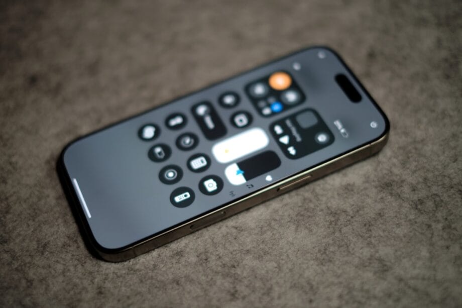 A smartphone displaying the control center screen rests on a gray textured surface.